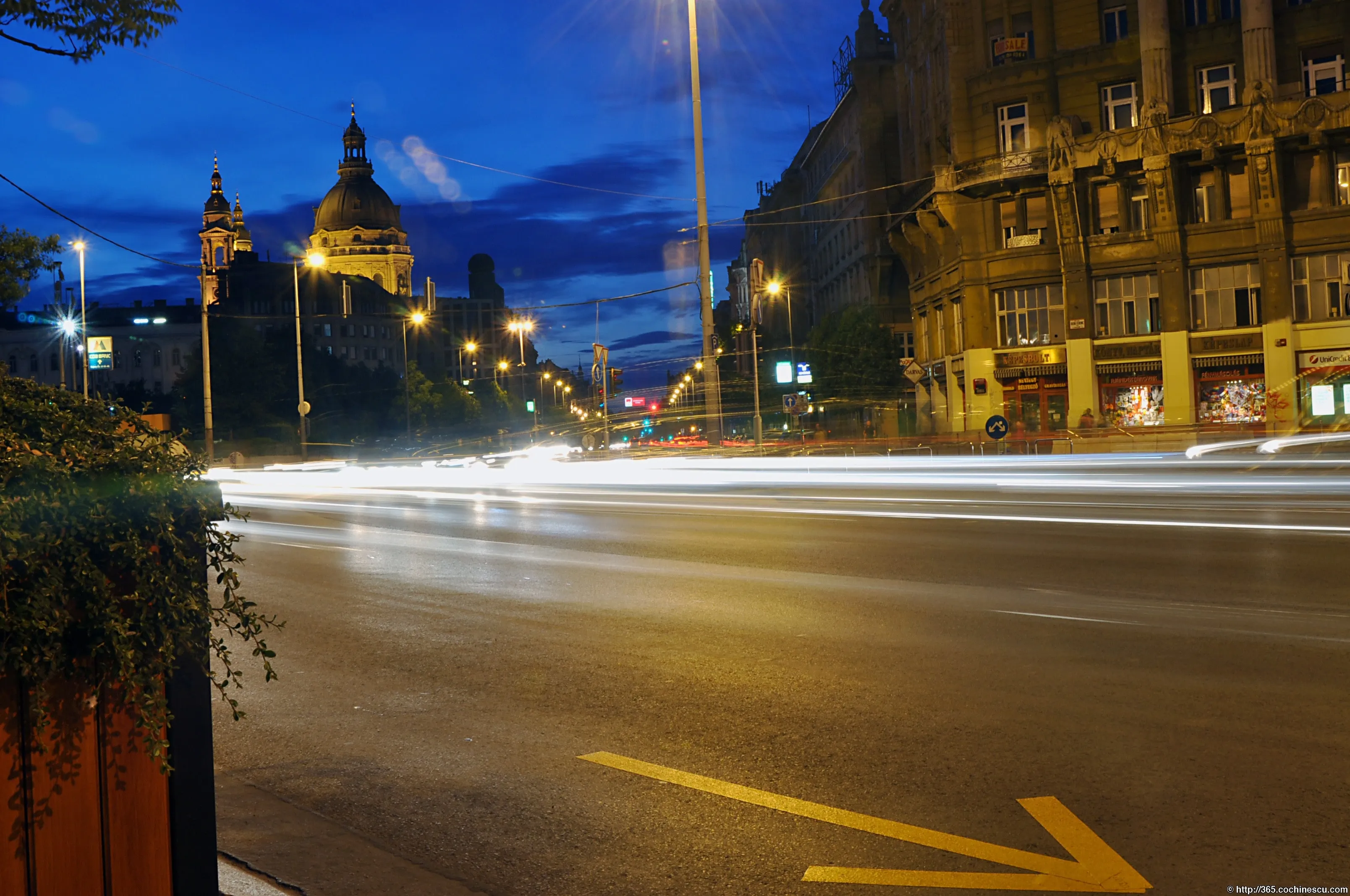 Dârele luminoase ale mașinilor traversează seara un bulevard din Budapesta.
