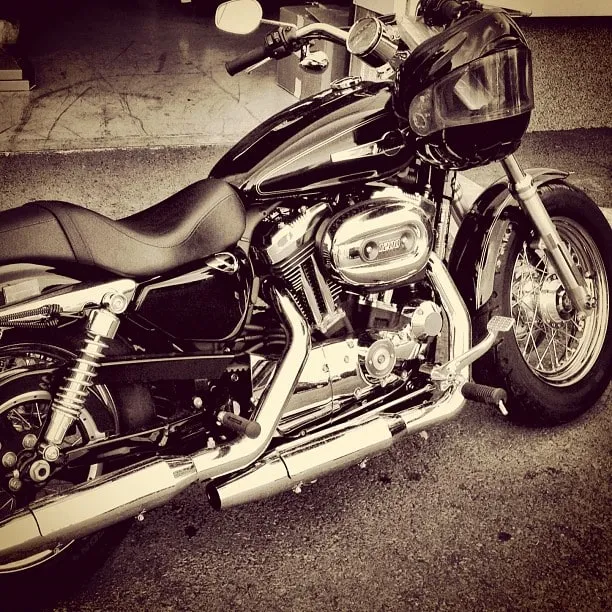 Black chrome motorcycle parked on asphalt with a helmet resting on the handlebars.