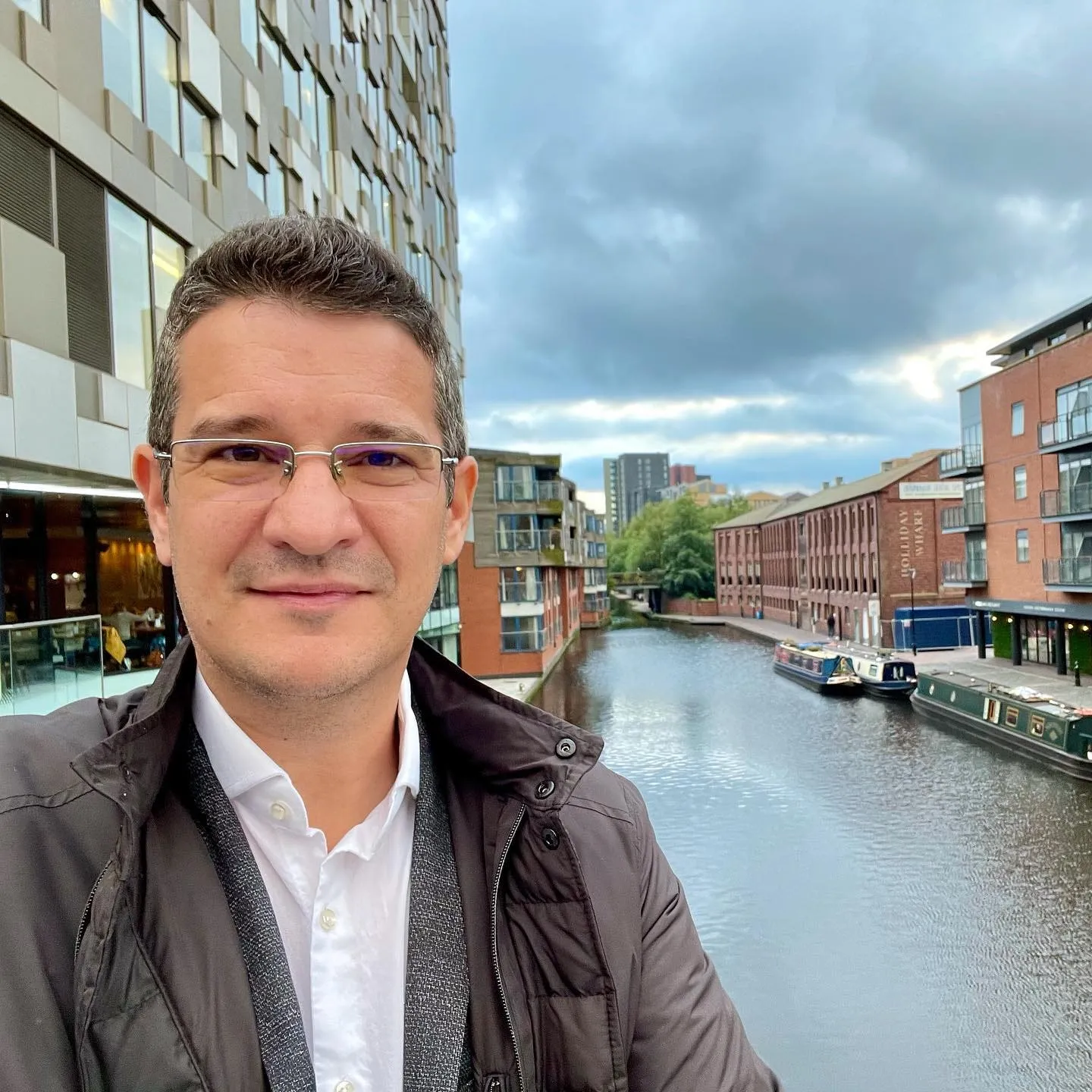 Sebastian Cochinescu își face un selfie lângă un canal din Birmingham, mărginit de clădiri din cărămidă și bărci înguste.