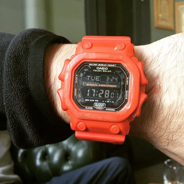 Close-up of a bright red Casio G-Shock digital watch on a wrist, displaying 17:28