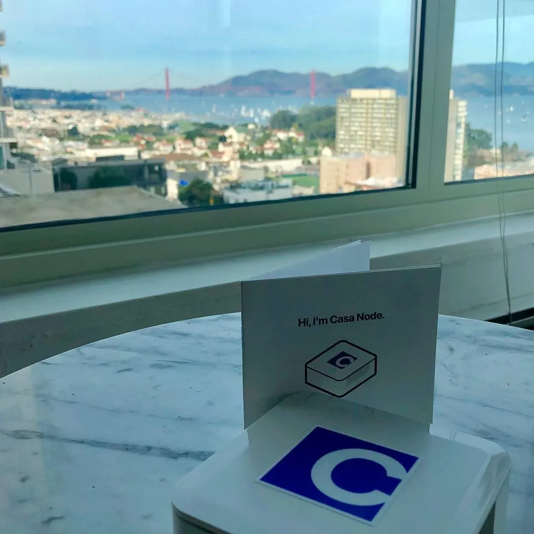 Casa Node card and blue C logo device on a marble table with the Golden Gate Bridge visible through a window