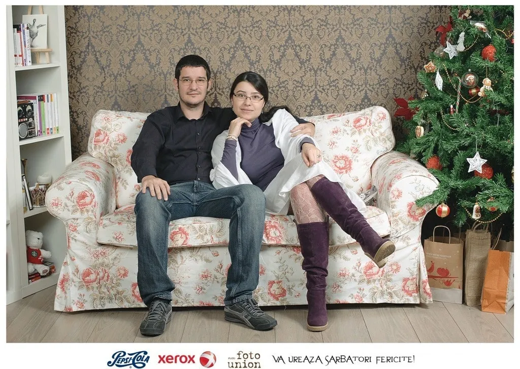 Cătălina și Sebastian stau împreună pe o canapea, lângă bradul de Crăciun.