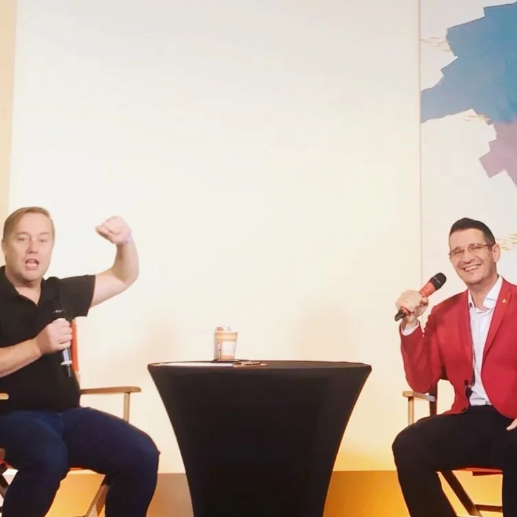 Jason Calacanis și Sebastian Cochinescu stau pe scenă, cu microfoanele în mână, în timpul unei conversații.