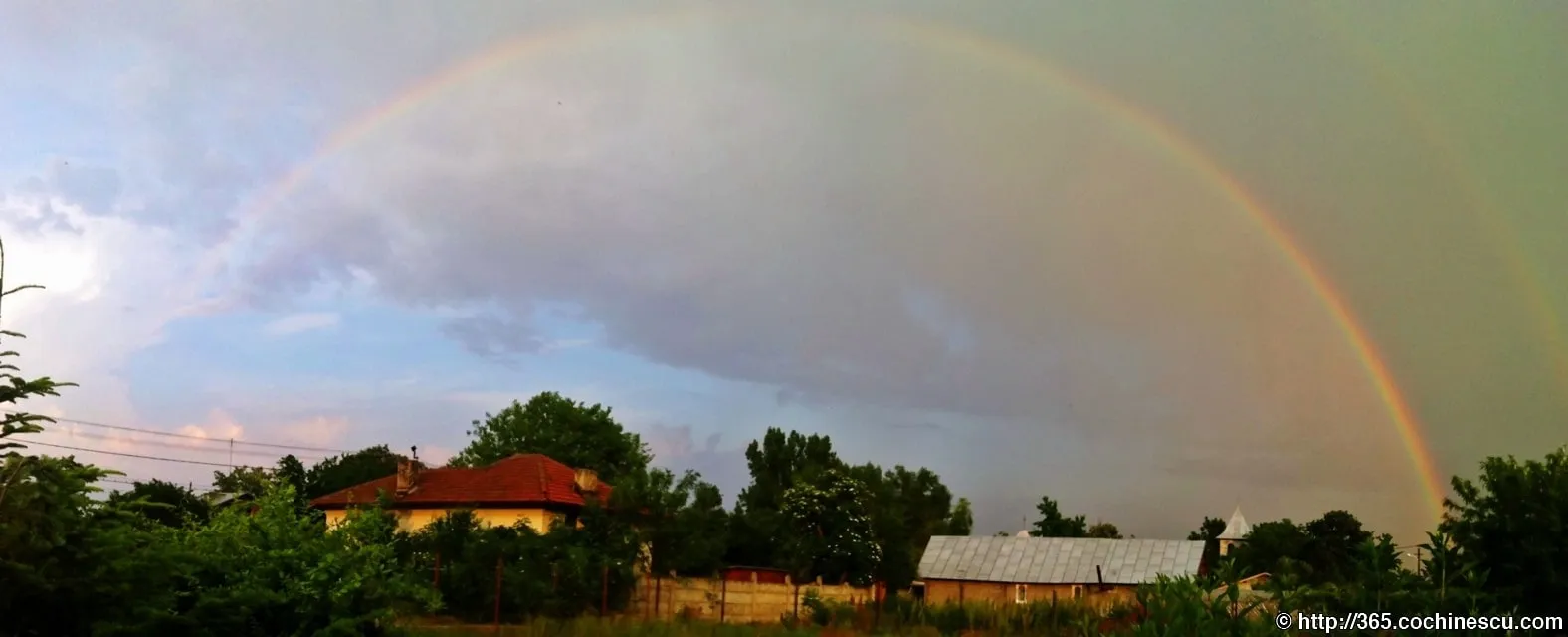 A double rainbow stretches over houses and trees in Ploiesti.