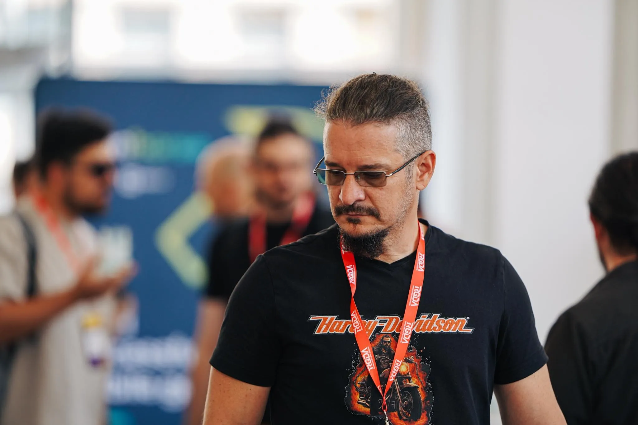 Sebastian Cochinescu stands thoughtfully among attendees at an indoor event.