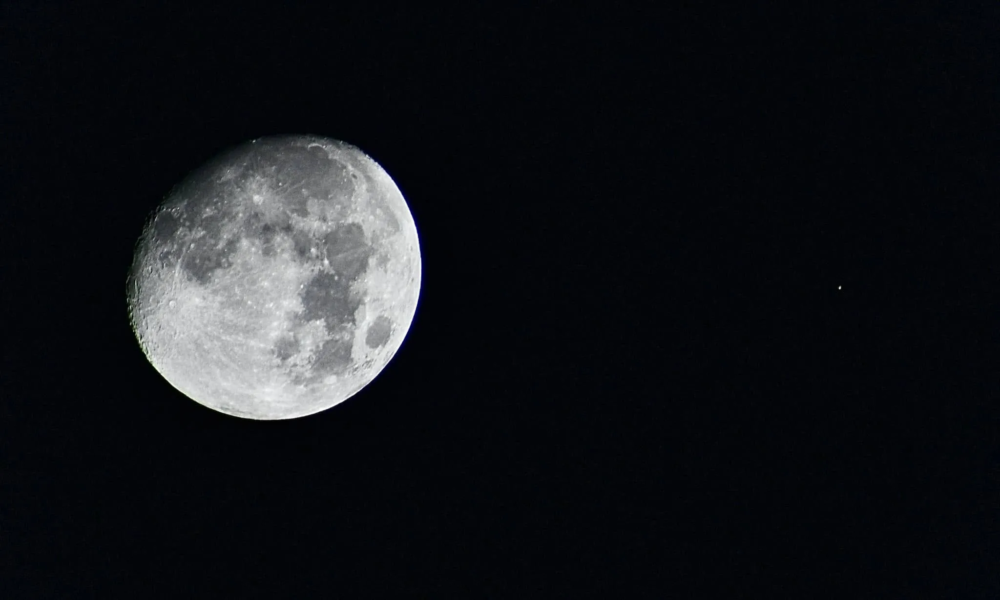 O lună aproape plină și un mic punct luminos, Marte, pe cerul negru al nopții.