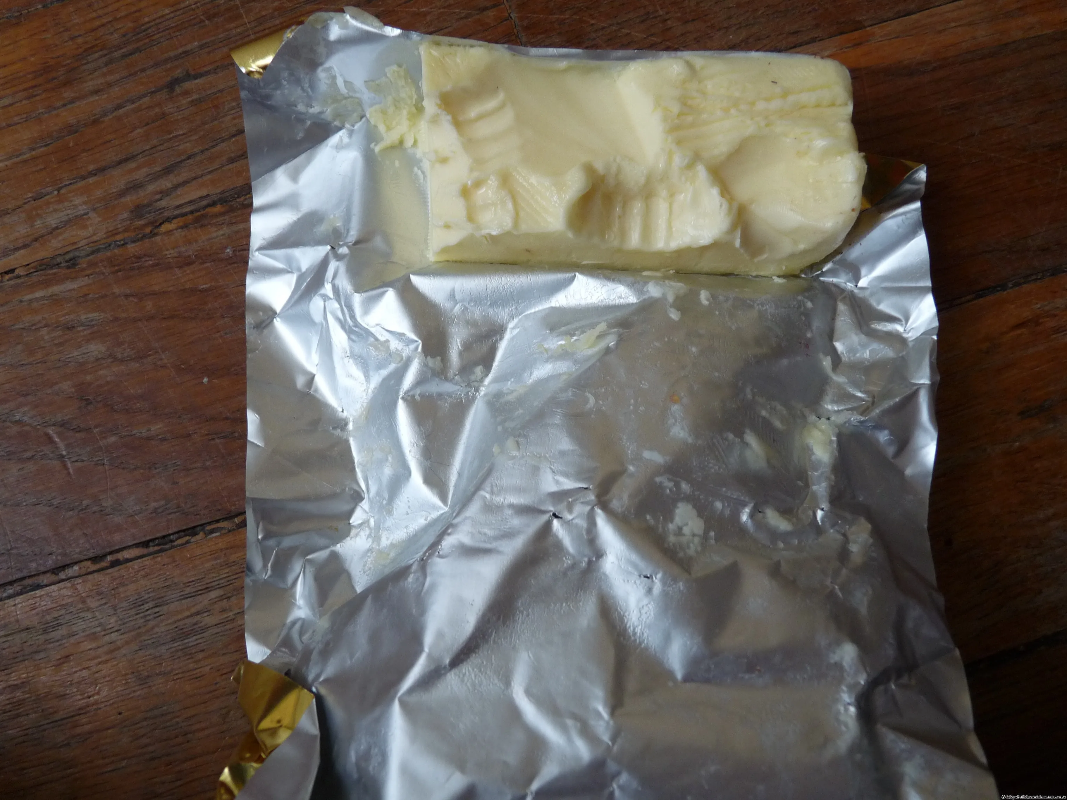 Un pachet de unt desfăcut pe o masă din lemn.