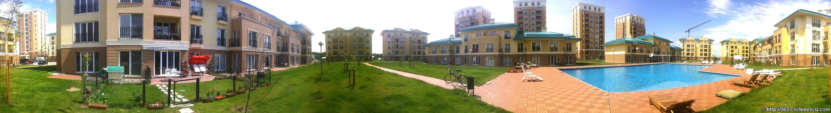 O panoramă largă arată piscina, spațiile verzi și blocurile complexului Cosmopolis.